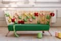 Green sofa with a woven wooden backrest adorned with colorful, knotted cushions in a bright room.