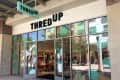 ThredUp store entrance with glass doors, mannequins, and clothing displays inside.