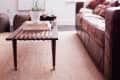 Living room with brown leather sofa, wooden coffee table, abstract art, and a floor lamp.