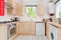 L-shaped kitchen with light wood cabinets, stainless steel oven, dishwasher, and washing machine under a window.