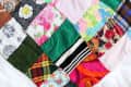 Colorful patchwork quilt with various patterns and a tray holding art supplies, including colored pencils and paper.