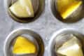 Lemon wedges in a muffin tin, each cup filled with water, ready to freeze.