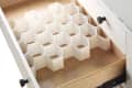 Open drawer with white honeycomb organizer inside a wooden dresser.