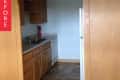 Small kitchen with wooden cabinets, dual sink, dishwasher, and fire extinguisher on tiled floor.