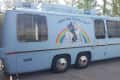 Light blue van with a mural of a person riding a unicorn over a rainbow, captioned "Follow Your Dreams, Fool!"