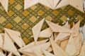 Wooden geometric floor pattern in progress with tools and cut pieces on a vintage patterned linoleum floor.