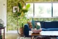 Living room with leafy wallpaper, blue sofa, large potted plant, and wooden coffee table with cactus centerpiece.