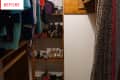 Cluttered closet with hanging clothes, shelves of shoes, and a leopard print curtain.