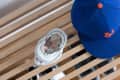 Baseball cap and ceramic dish with coins on a wooden slatted surface.