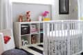 Modern nursery with a round white crib, black and white striped rug, and a woven pendant light.