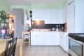 Bright kitchen with white cabinets, blackboard backsplash, coffee maker, blender, and stainless steel appliances.
