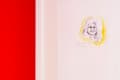 Framed sketch of a smiling woman with yellow highlights on a red wall.