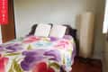 Bedroom with floral bedspread, two white pillows, and a tall floor lamp.