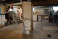 Basement with exposed brick, toilet, stairs, storage shelves, and various household items.