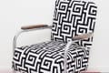 Retro chair with black and white geometric pattern, metal frame, and wooden armrests on red and white checkered floor.