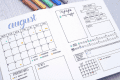 August bullet journal spread with calendar, to-do list, notes, and colorful pens.