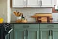 Kitchen with white upper cabinets, green lower cabinets, black countertop, and geometric tile floor.
