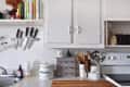 Kitchen counter with knives on a magnetic strip, cookbooks, utensils in jars, and a compost bin.