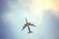 Airplane flying overhead against a blue sky with clouds.