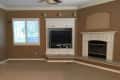Living room with brown walls, white entertainment center, TV, and fireplace.