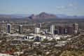 Cityscape of Phoenix with tall buildings and Camelback Mountain in the background.