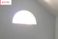 Arched window on a plain wall with sunlight streaming through.