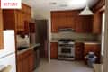Wooden kitchen cabinets, granite countertops, white fridge, stainless steel dishwasher, and gas stove under a pendant light.