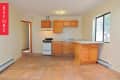 Empty kitchen with terracotta tile floor, wooden cabinets, small stove, and large window.