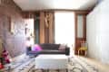 Living room with a gray sofa, colorful pillows, white coffee table, brick wall, and mounted deer head decor.