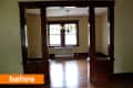 Empty dining room with wooden trim, chandelier, and large windows.