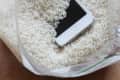 Smartphone submerged in a plastic bag filled with uncooked rice