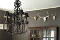 A dining room with animal skulls on the wall and a black chandelier above the table.