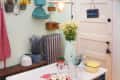 Vintage kitchen with daisies in a pitcher, lavender, mason jars, and a farmhouse sign on a door.