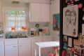 Bright kitchen with white cabinets, a small island, and a fridge covered in drawings and magnets.