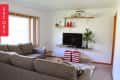 Living room with gray sofas, wall-mounted TV, red-striped baskets, and a potted plant on a shelf.