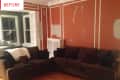 Living room with brown sofas, orange walls with white trim, and a bay window with plants.