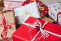 Assorted wrapped gifts with red, white, and gold paper, adorned with ribbons and bows.