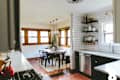 Kitchen with white subway tiles, open shelves, and a dining area with a wooden table and black chairs.