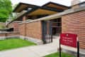 Frederick C. Robie House exterior with red brick walls, modern design, and a red sign on the lawn.