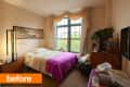 Small bedroom with a bed, purple blanket, large window, and wall art.