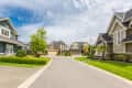 Suburban neighborhood with modern houses, manicured lawns, and a clear sky.