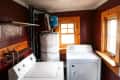 Laundry room with white washer and dryer, maroon walls, wooden window frames, and a water heater.