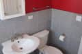Small bathroom with red walls, white sink, toilet, and gray tile.