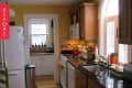 Yellow kitchen with wooden cabinets, black countertops, white appliances, and a red kettle on the stove.