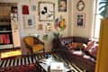 Living room with a brown leather sofa, colorful pillows, wall art, a yellow chair, and a dog resting on the couch.