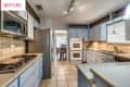 Spacious kitchen with light blue cabinets, stainless steel appliances, and tiled backsplash, leading to dining area.