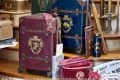 Hogwarts-themed luggage with Gryffindor, Slytherin, and Ravenclaw crests, surrounded by travel accessories and an owl.
