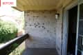 Small balcony with brick wall, sliding glass door, and outdoor light fixture.