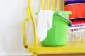 Yellow chair with a green bucket and white cloth, colorful blanket draped over, and a green bowl with a cloth on the floor.