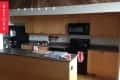 Wooden kitchen cabinets, black appliances, and a countertop with a cutting board and candle, labeled "Before."